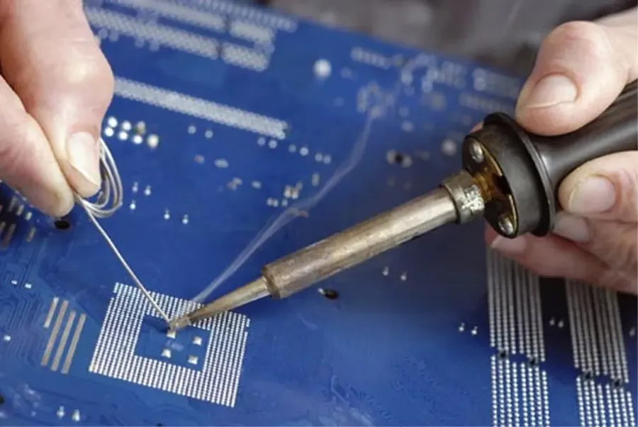 A close up of a hand soldering components onto a printed circuit board.