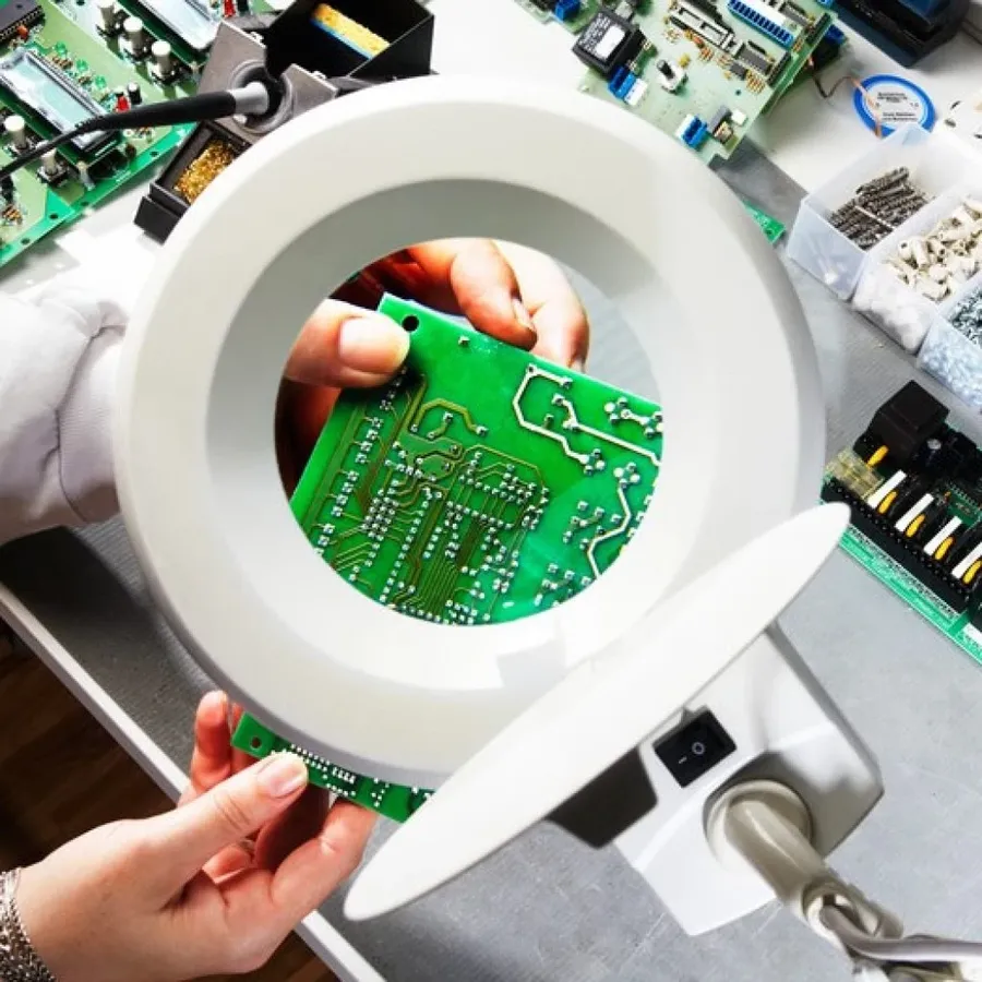 A worker inspecting a PCB with tools.